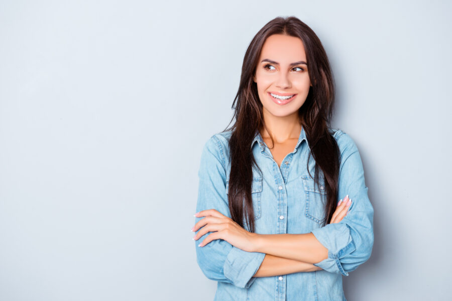 Attractive brunette with crossed hands isolated on gray background